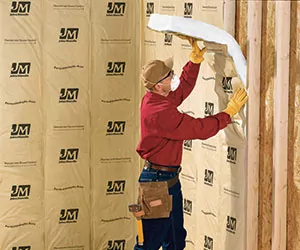 Worker installing fiber glass insulation