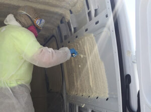 Worker installing foam insulation on a pest control vehicle