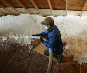 Worker Installing Blow-in Insulation in an Attic; by Delmarva Spray Foam in Georgetown, Delaware