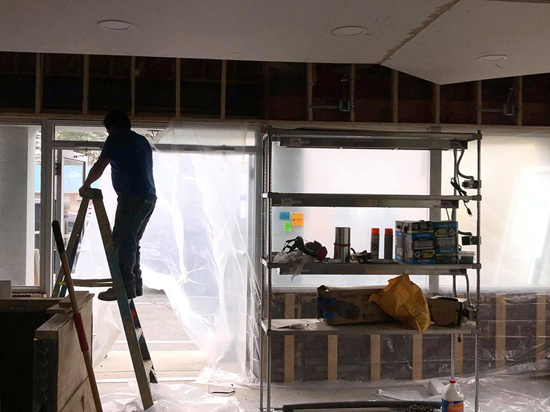 Worker installing spray foam in the walls of a new restaurant.