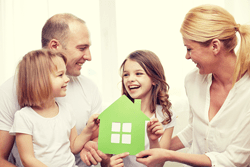 Family holding a green paper house cutout.