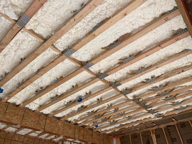 Open cell spray foam applied in a garage ceiling to keep second floor rooms warm.