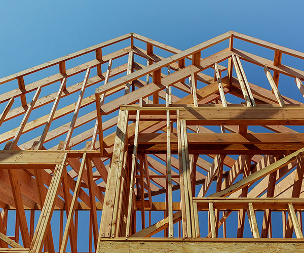 New-Construction Wooden frame structure of a house under construction against a clear blue sky