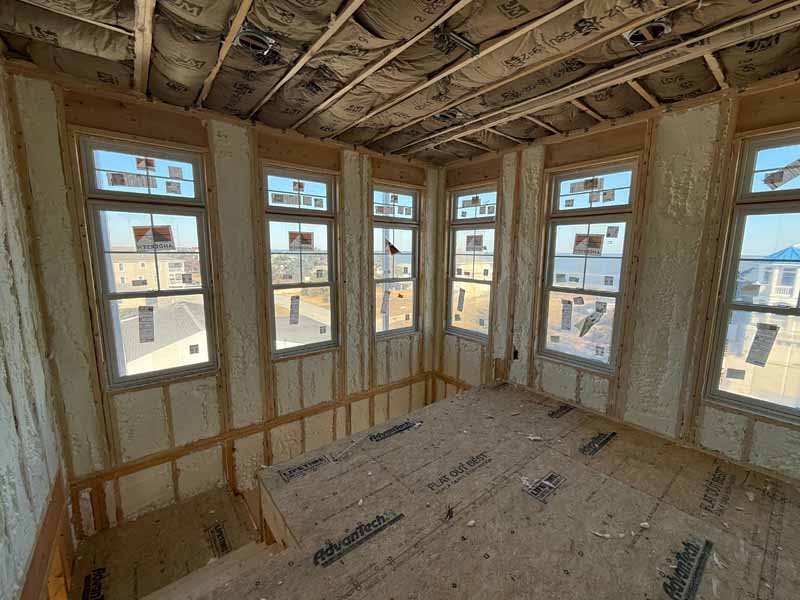 Residential room with multiple framed windows insulated with spray foam along exterior walls.