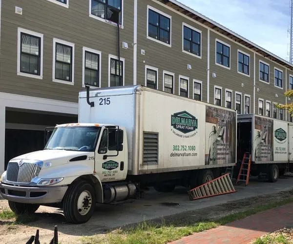Delmarva Spray Foam Insulation truck parked in front of a multi-story residential building under construction.